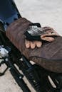 Leather gloves resting on a classic motorcycle seat in an outdoor setting, embodying adventure.